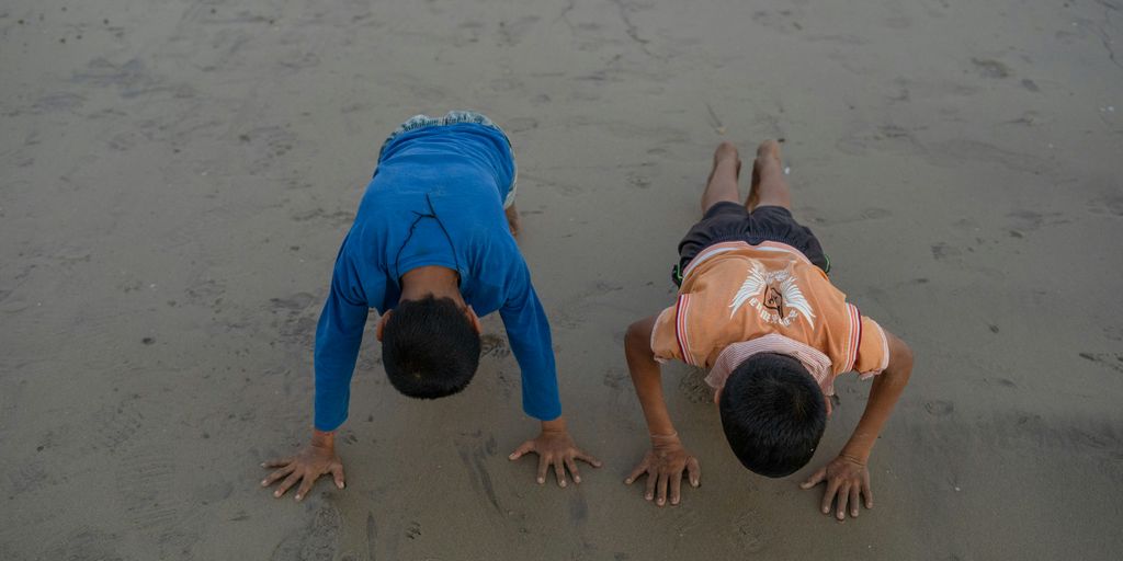 two young boys are playing on the beach