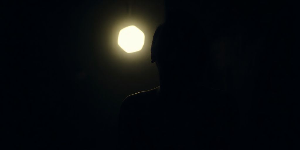 Man meditating in dark room with subtle light.