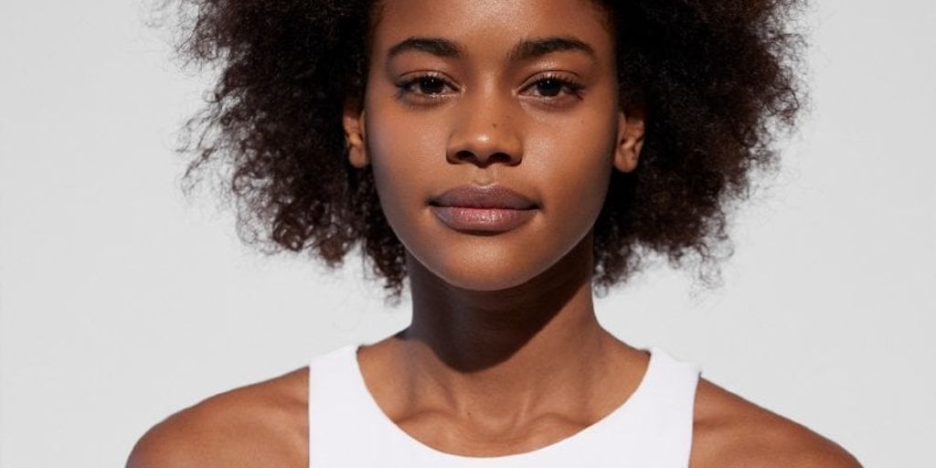 Portrait of a woman with curly hair, wearing a white top.