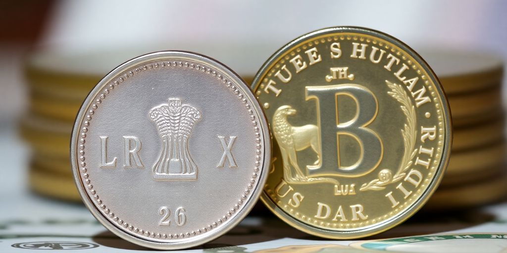 Indian Rupee and US Dollar coins side-by-side against a blurry background.
