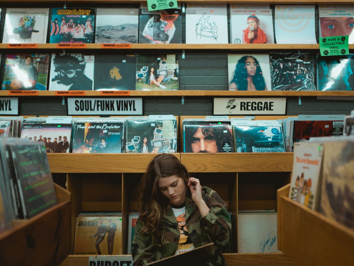 woman in green jacket standing beside books