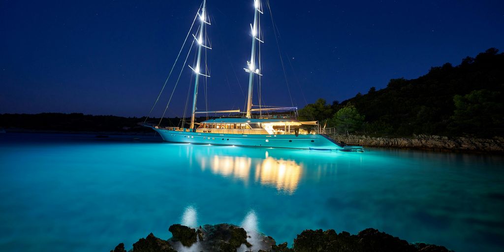 brown and white sail boat on blue body of water during night time