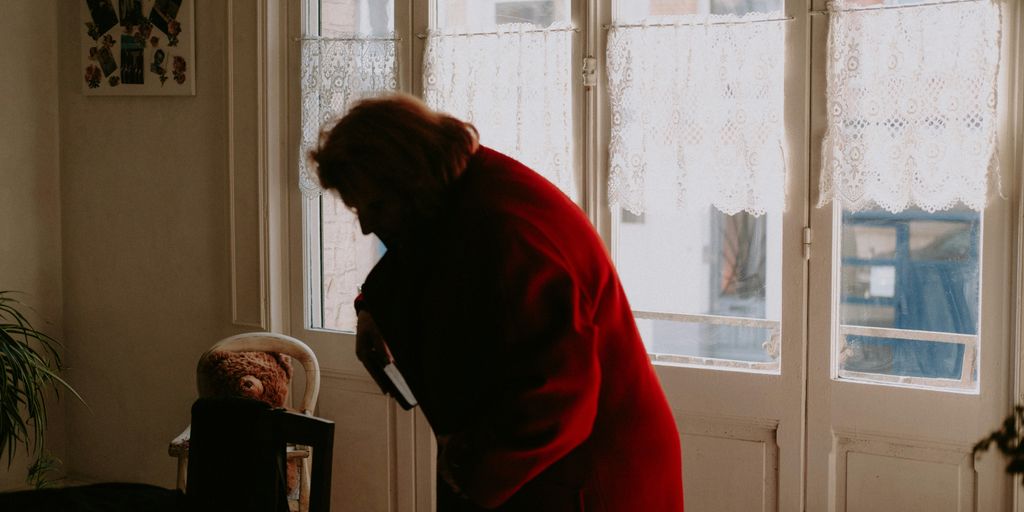 a woman in a red coat looking at a teddy bear