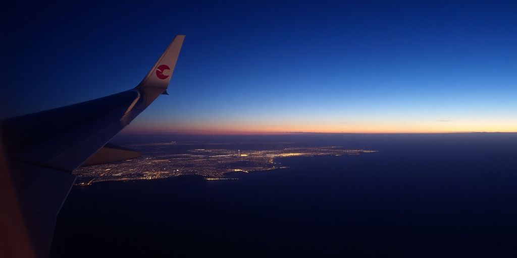 An airplane wing over the Orange County coast at dusk.