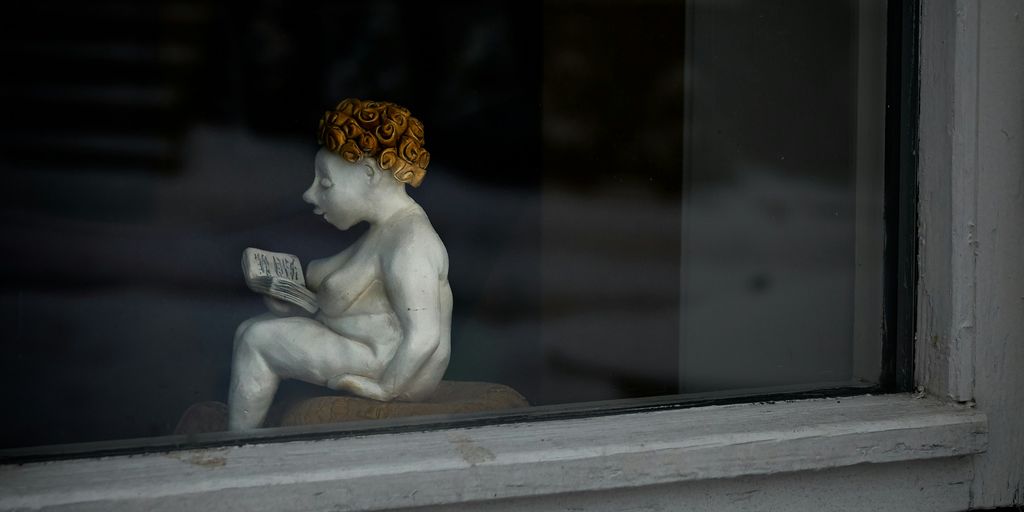 woman reading book figurine by the window
