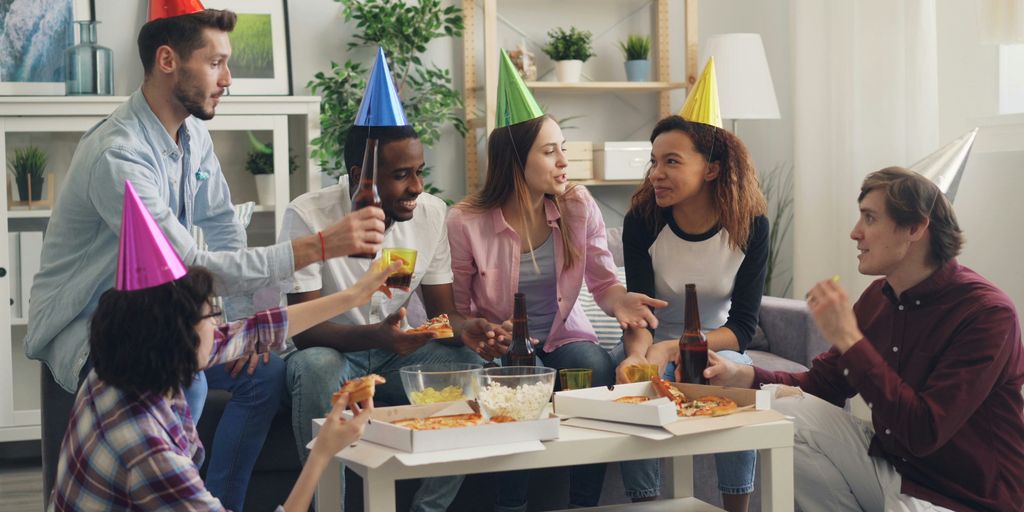 a group of people sitting around a table wearing party hats