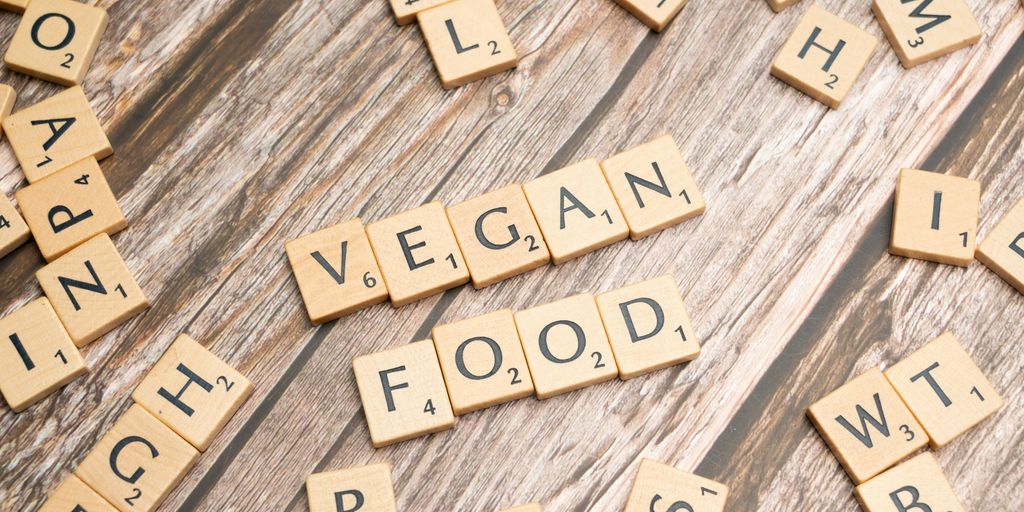 a wooden table topped with scrabble tiles spelling vegan food