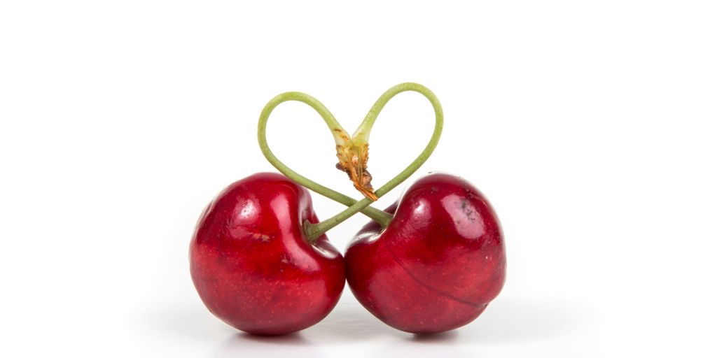 two red cherry fruits on white surface
