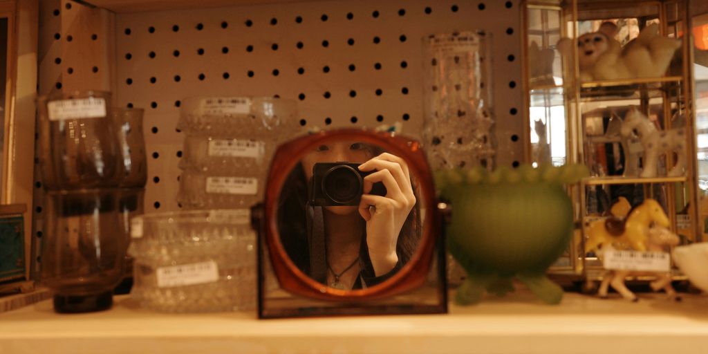 A person takes a photo in a display mirror.