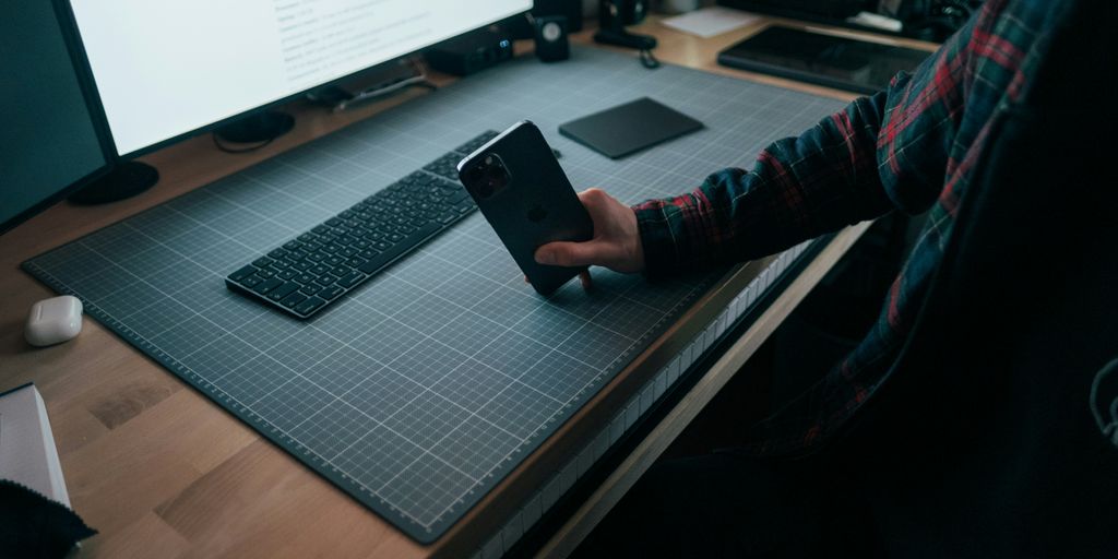 person in red and black long sleeve shirt holding black smartphone
