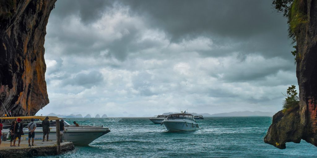 white boat on body of water under cloudy sky