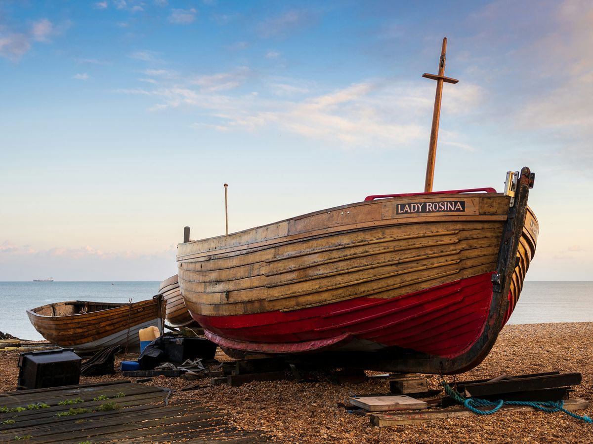 a boat sitting on top of a beach next to the ocean