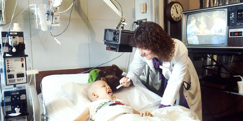 child lying on bed while doctor checking his mouth