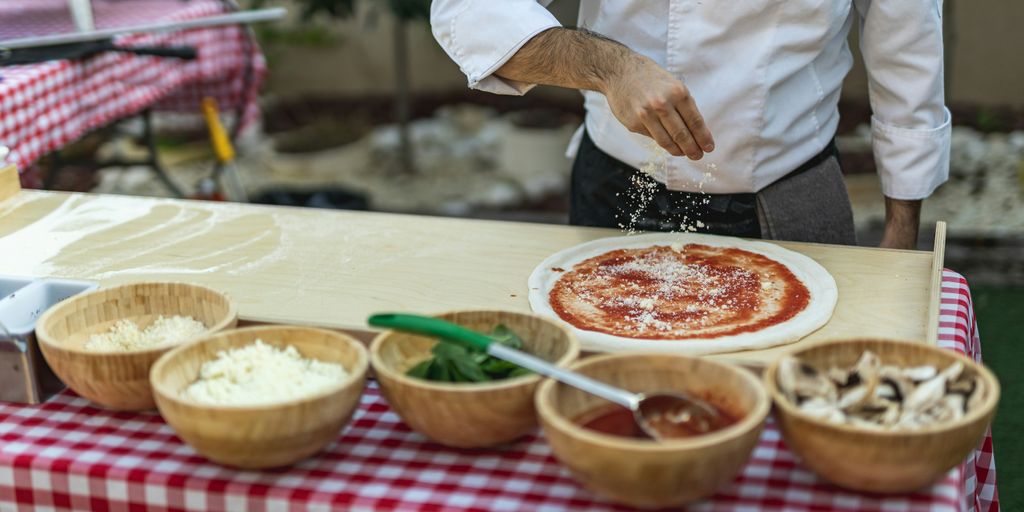 a man is sprinkling cheese on a pizza