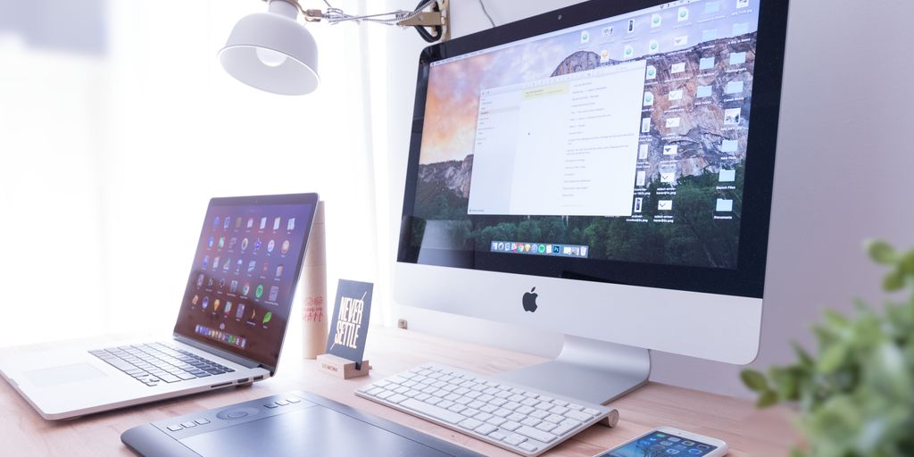 silver iMac near iPhone on brown wooden table
