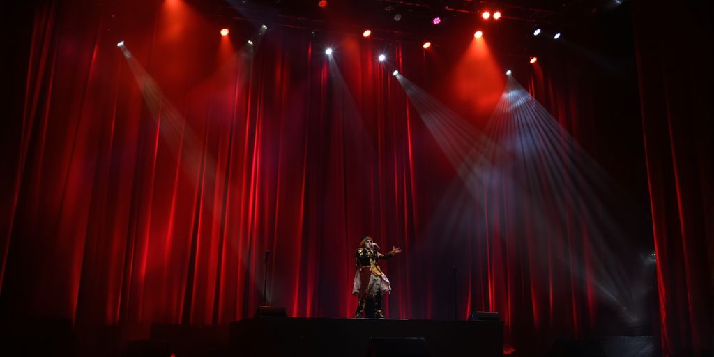 A stage bathed in colorful light, performers mid-gesture.