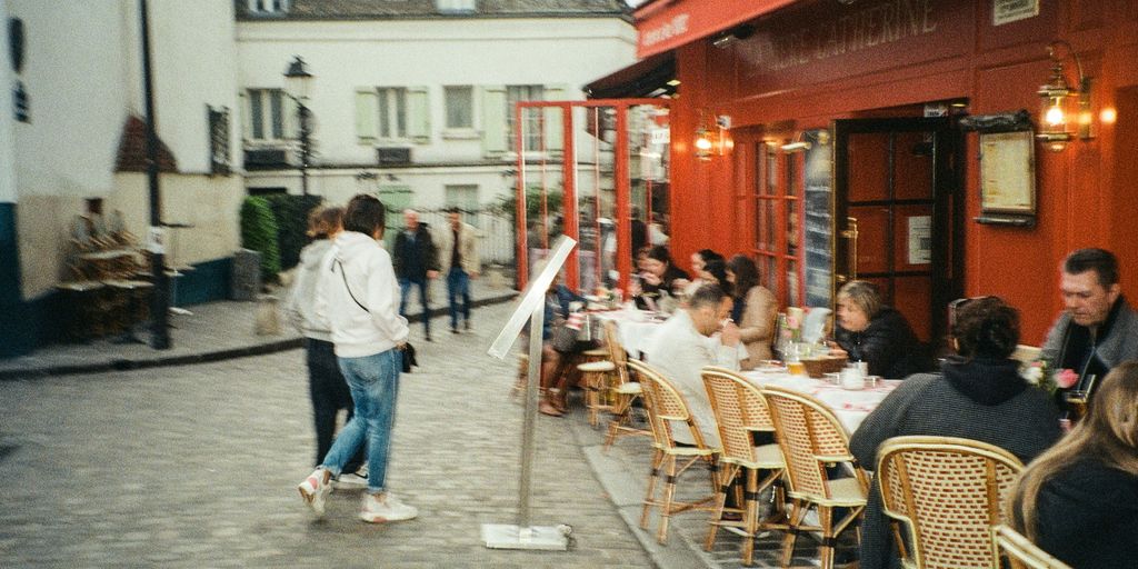 a group of people sitting at tables outside of a restaurant