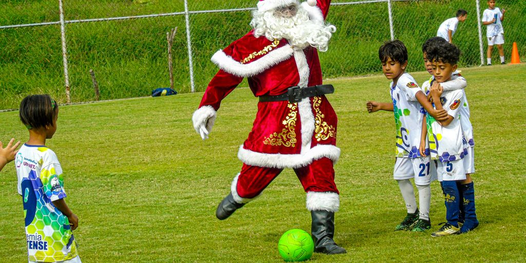 A man dressed as santa claus kicking a soccer ball
