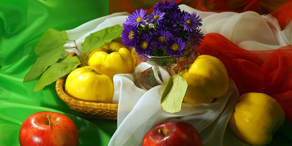 a basket filled with fruit and flowers on top of a green cloth