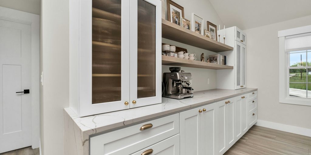 a kitchen with white cabinets and wood floors