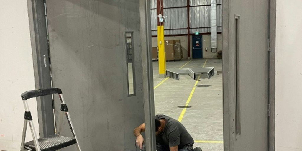 A man kneeling down next to a metal door