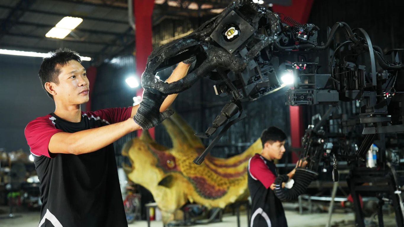 Two individuals working on robotic machinery in a workshop.