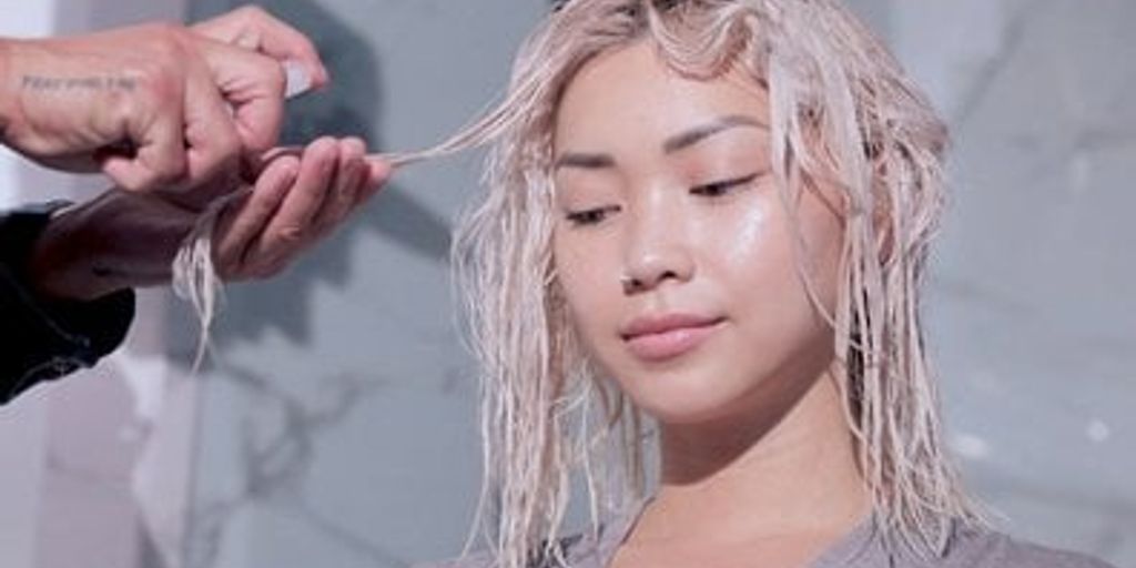 Person getting hair styled with product, salon setting, content expression.