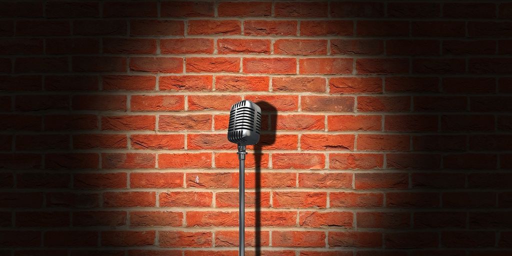 A classic microphone illuminated against a brick wall backdrop.