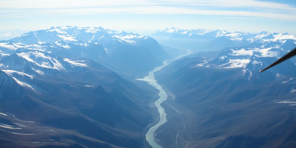 A red helicopter flies over a vast Alaskan mountain range.