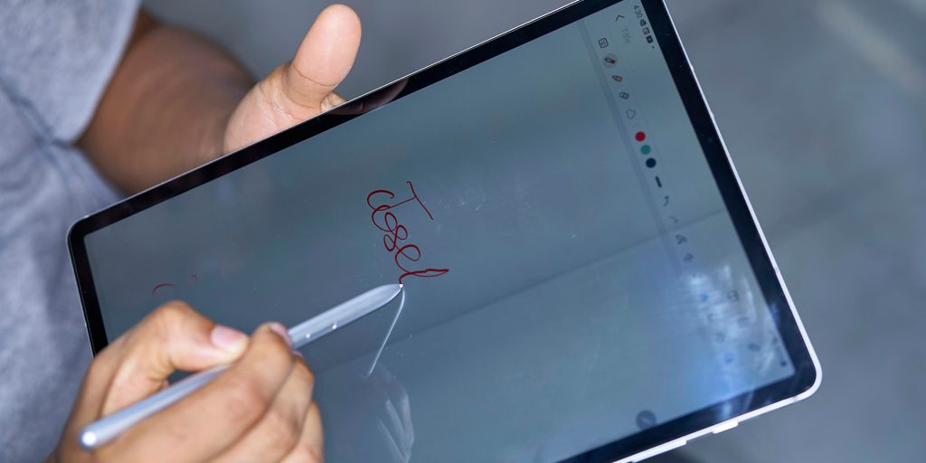 a person writing on a tablet with a pen