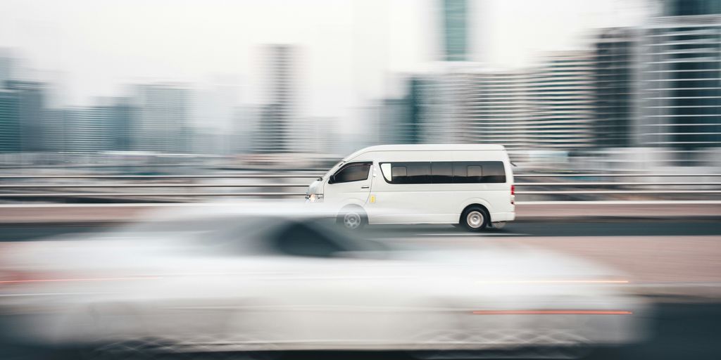 a white van driving down a street next to tall buildings