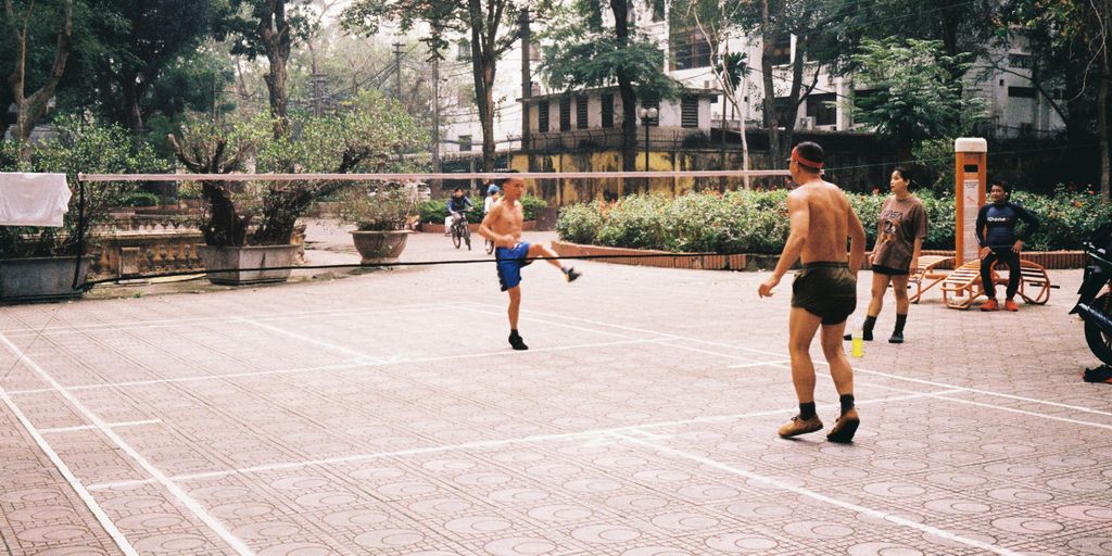 Men play foot-volleyball in an outdoor park.