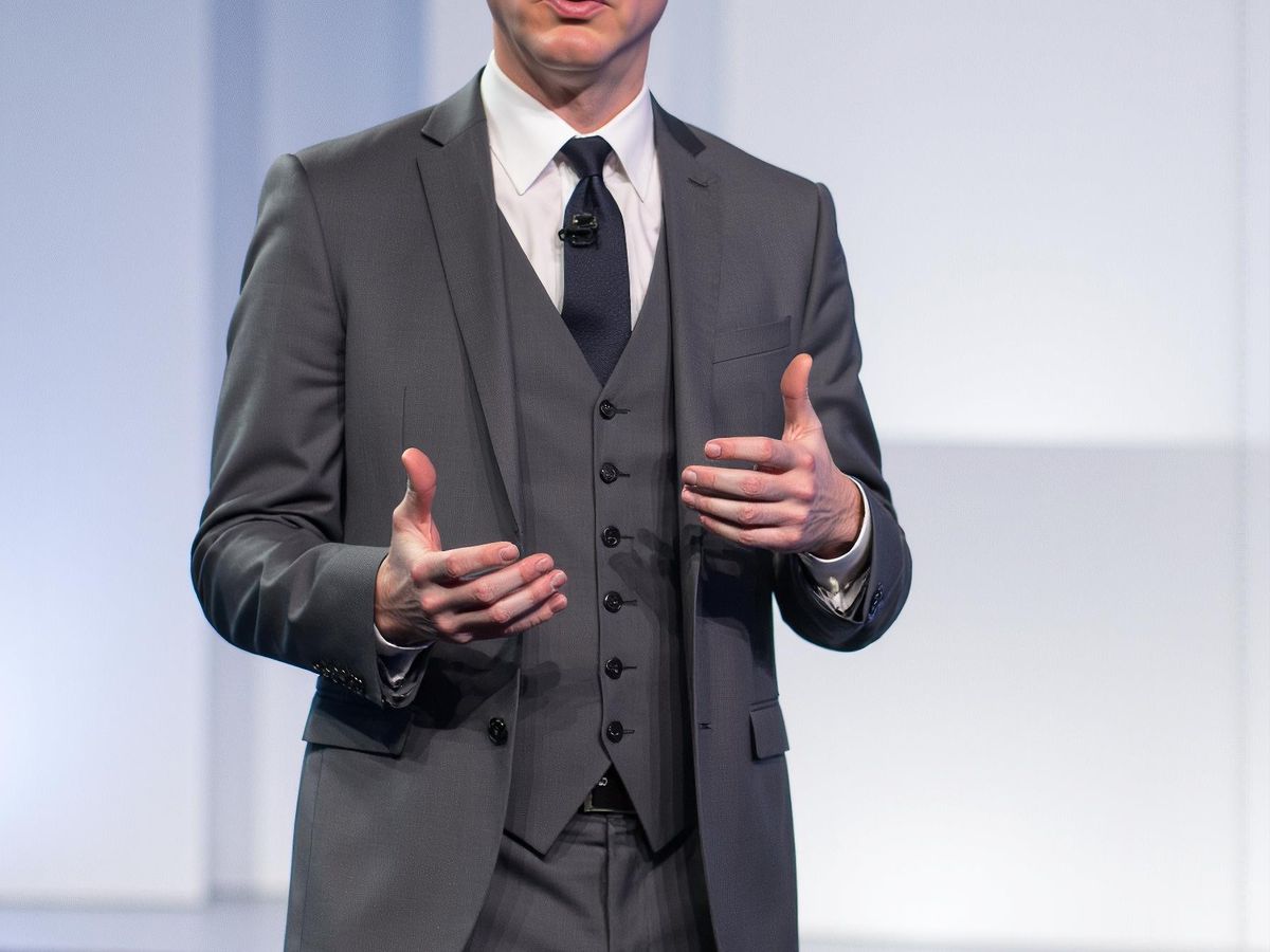 A person in a suit delivering a presentation on stage.