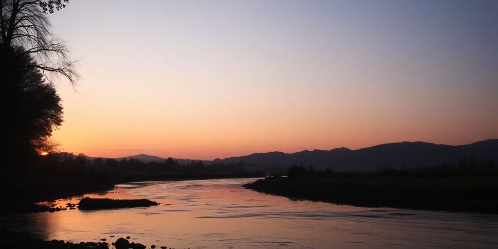 Silhouetted landscape with a peaceful stream at dusk.
