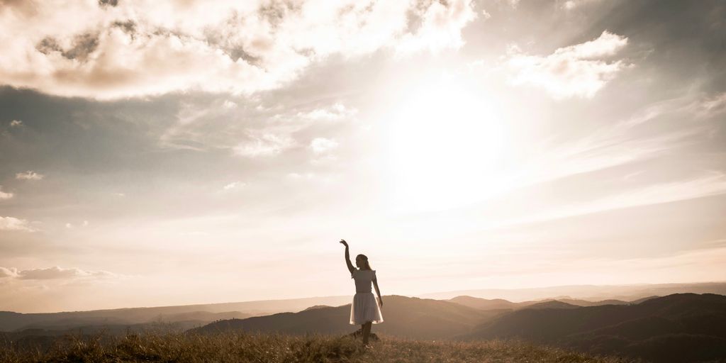 a woman standing on top of a grass covered hillside