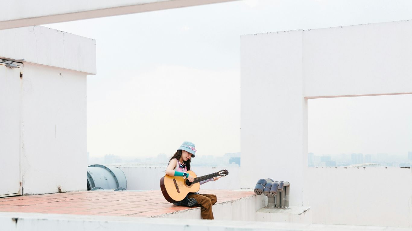 a woman sitting on a ledge playing a guitar