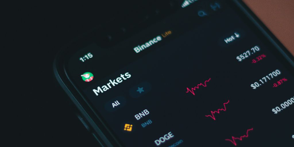 A close-up of a smartphone displaying cryptocurrency market graphs.