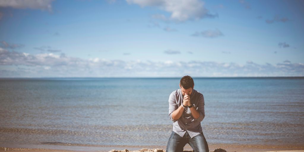 man kneeling down near shore