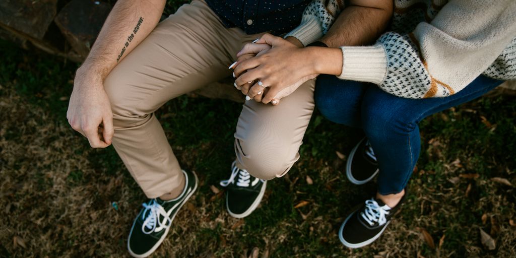 woman in black shirt and blue denim jeans sitting on brown wooden bench