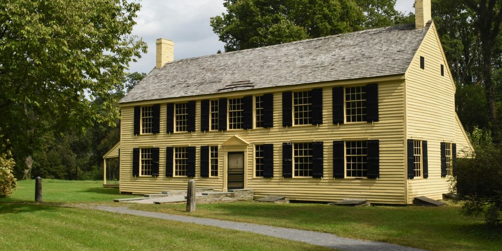 a large yellow house sitting on top of a lush green field