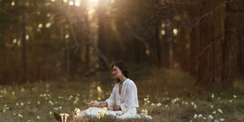 a woman sitting in the middle of a forest
