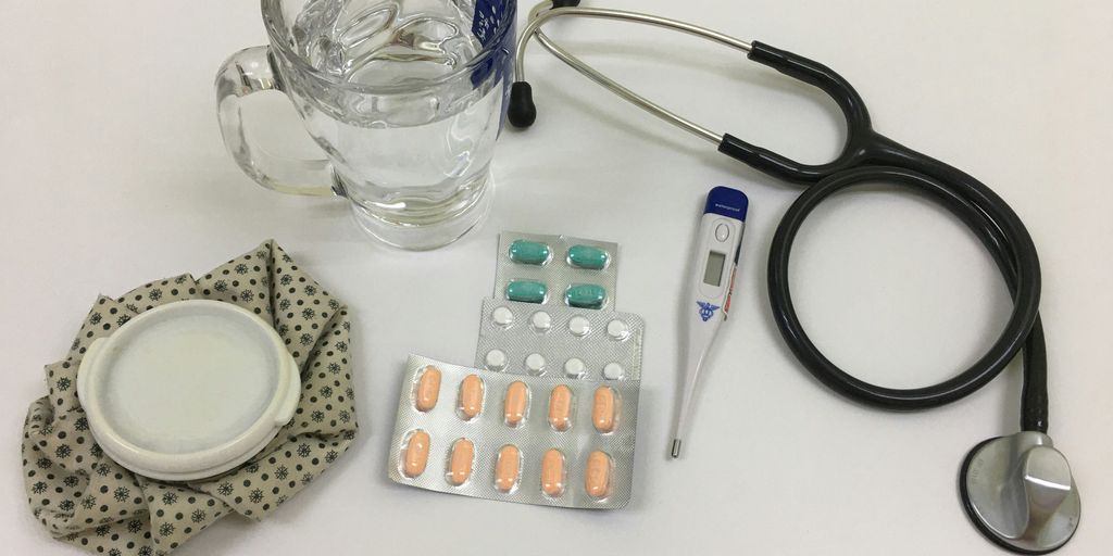 black and silver stethoscope beside clear glass mug