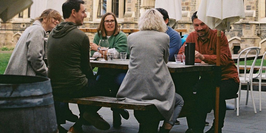 A group of people sitting at a table outside