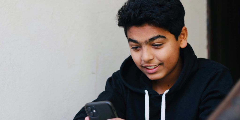 man in black and white hoodie holding black smartphone