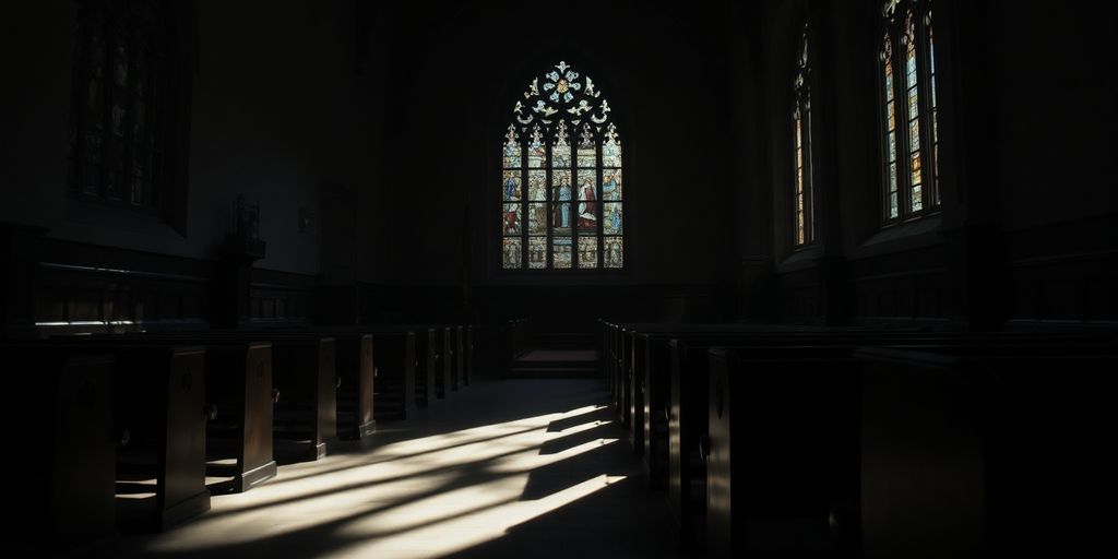 Empty church with dark lighting and stained glass windows.