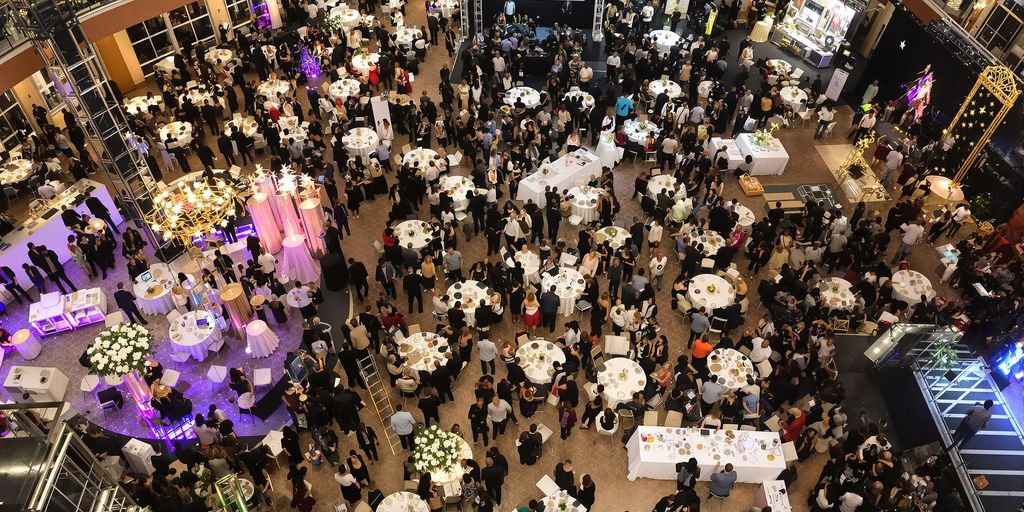 Organized event space with people mingling and stages.