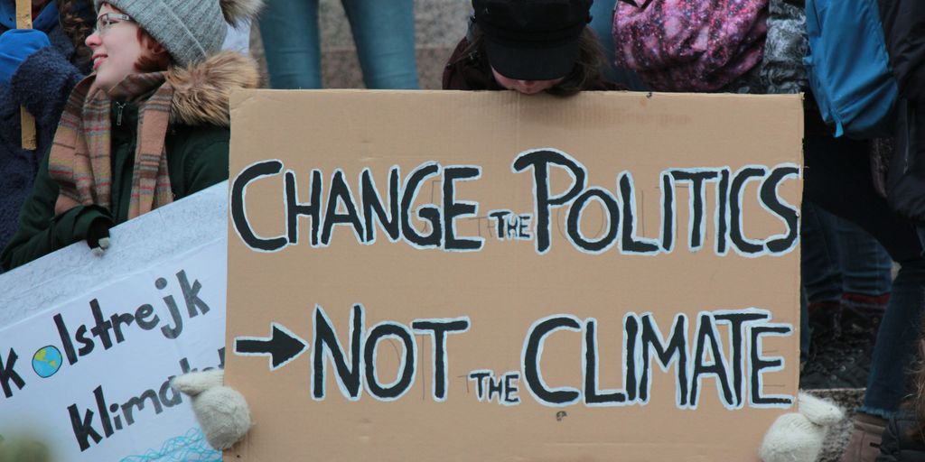 person holding change the politics not the climate printed board