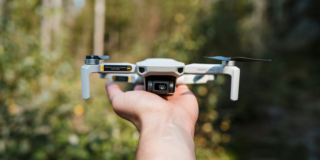 a person holding a small white and black remote controlled flying device