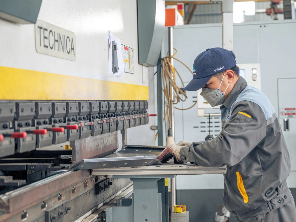 A worker operates a machine in a manufacturing environment.