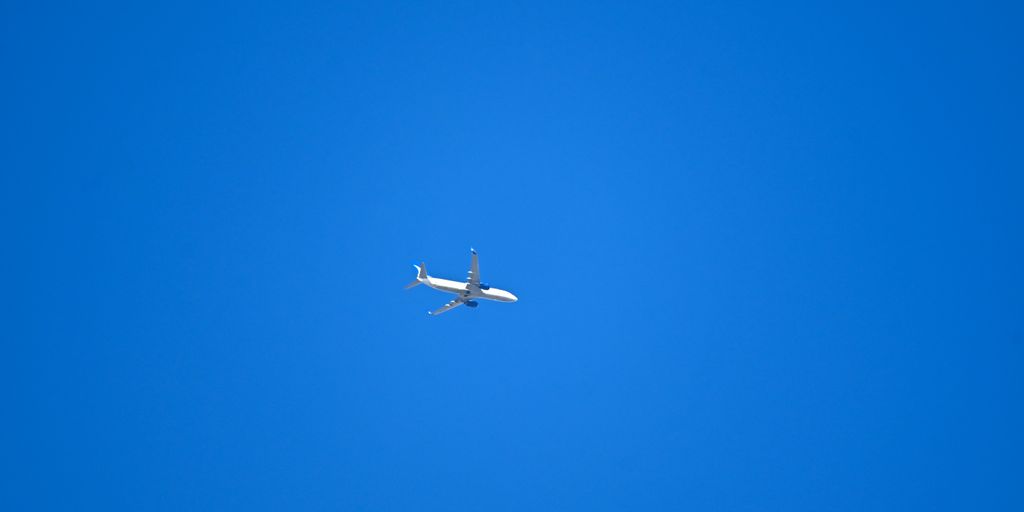 An airplane is flying in the blue sky